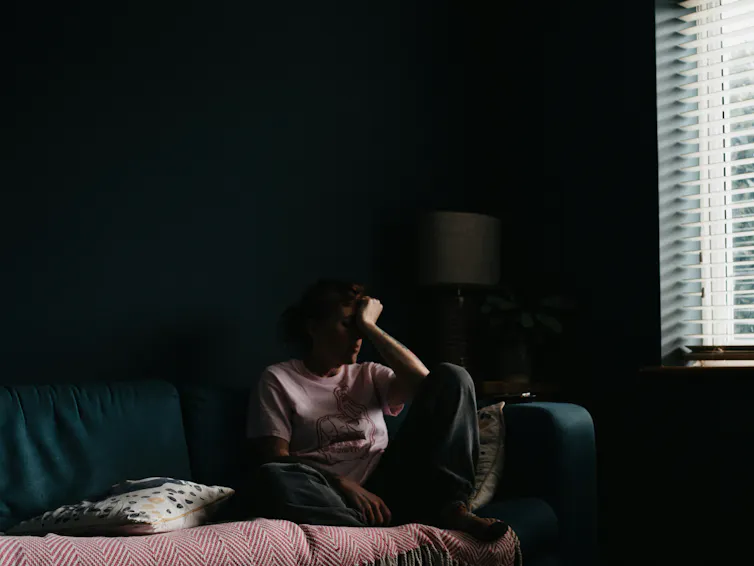 woman sitting on couch with head in hand