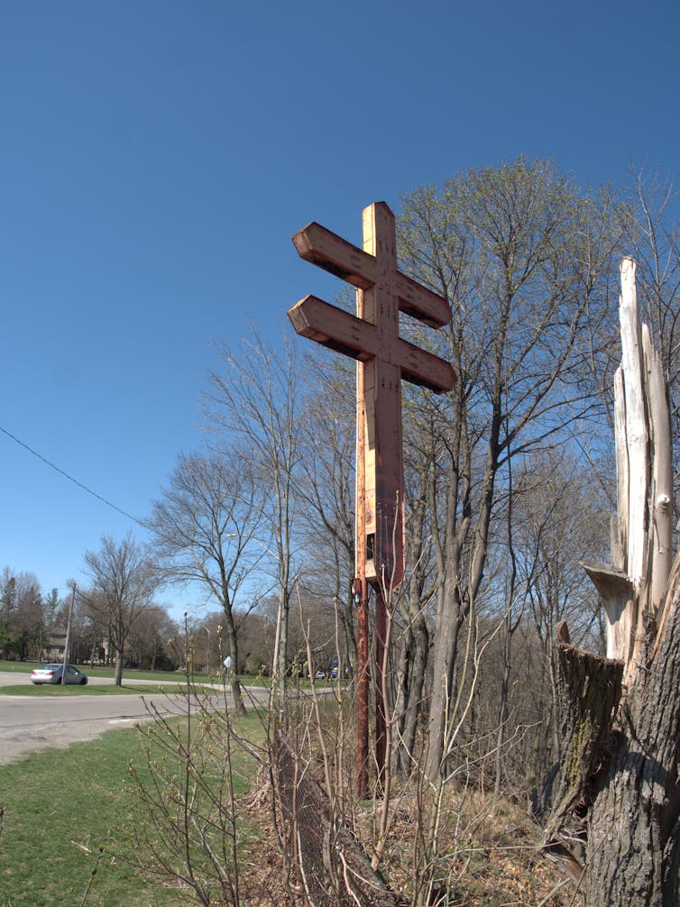 A large cross with two horizontal beams on the side of a road