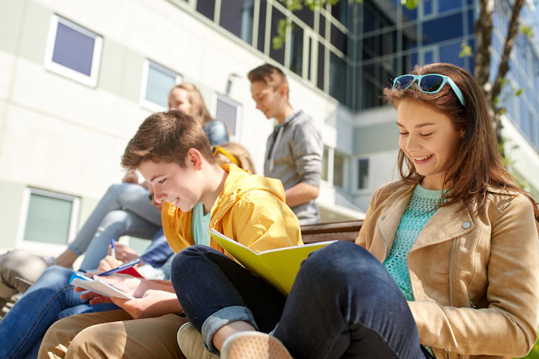 A group of teenagers sit outside and study happily