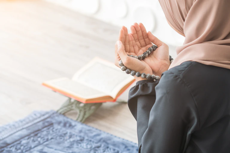 A woman prays besides a copy of the Qua'ran.