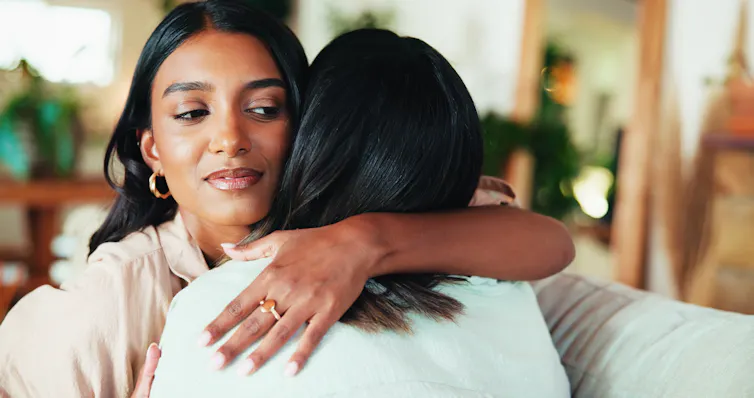 A woman hugs her friend.