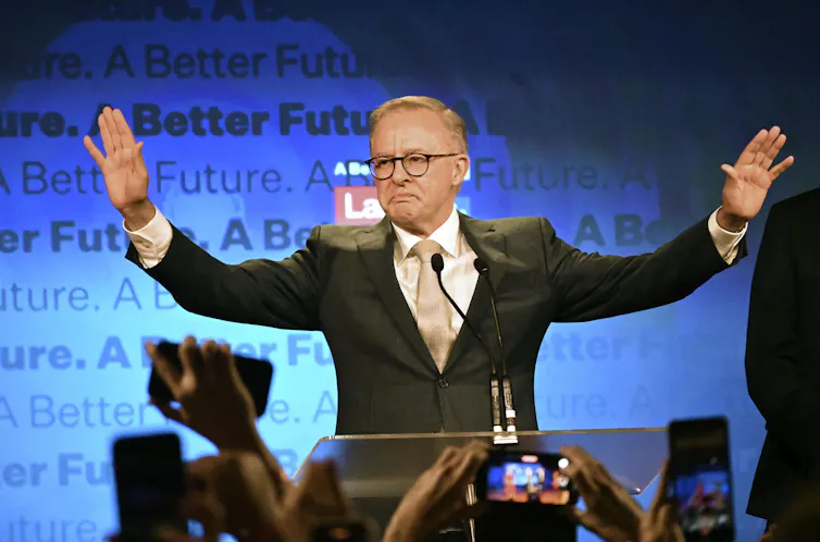 Anthony Albanese stands in a suit waving to a crowd.