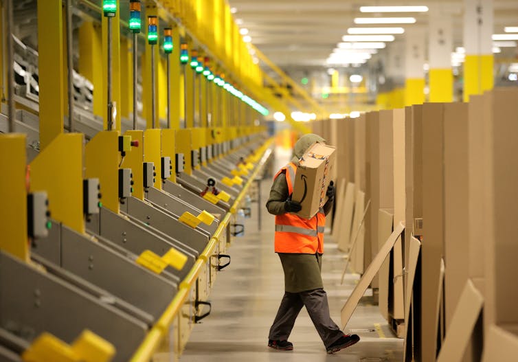 A factory worker carries a box in a warehouse