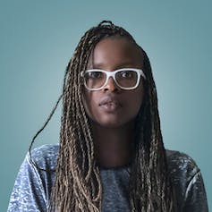 A serious-looking Black woman with long hair and sunglasses