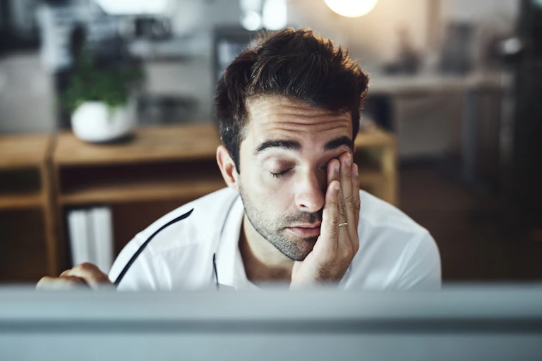 A tired man working on a computer.