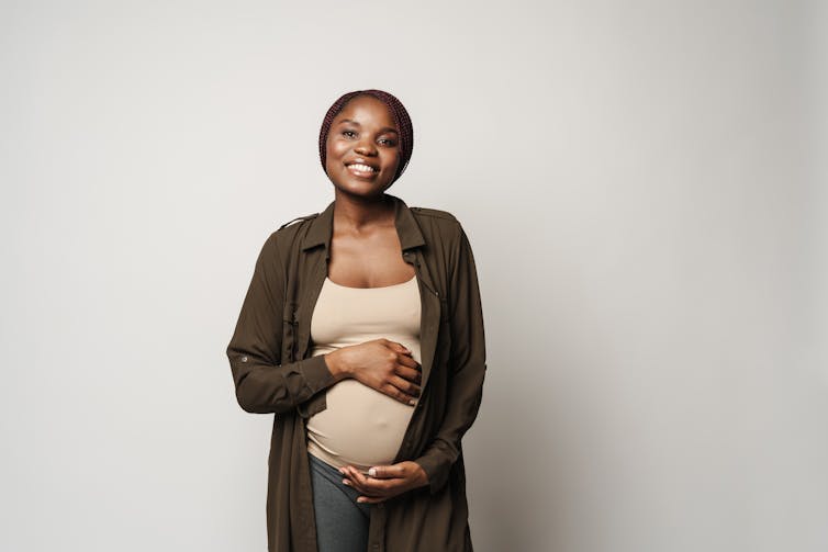 A pregnant woman caresses her bulge with both hands.