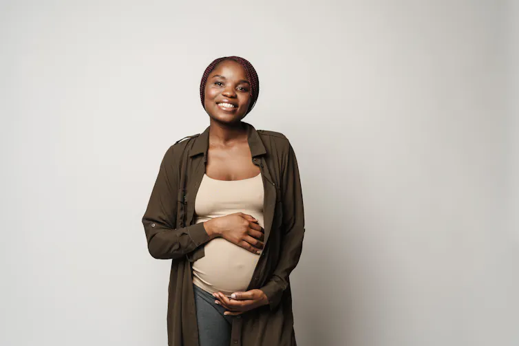 A pregnant woman caresses her bulge with both hands.