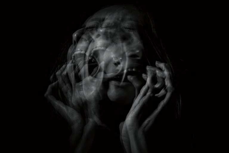 A woman screaming against a black nightmarish background.