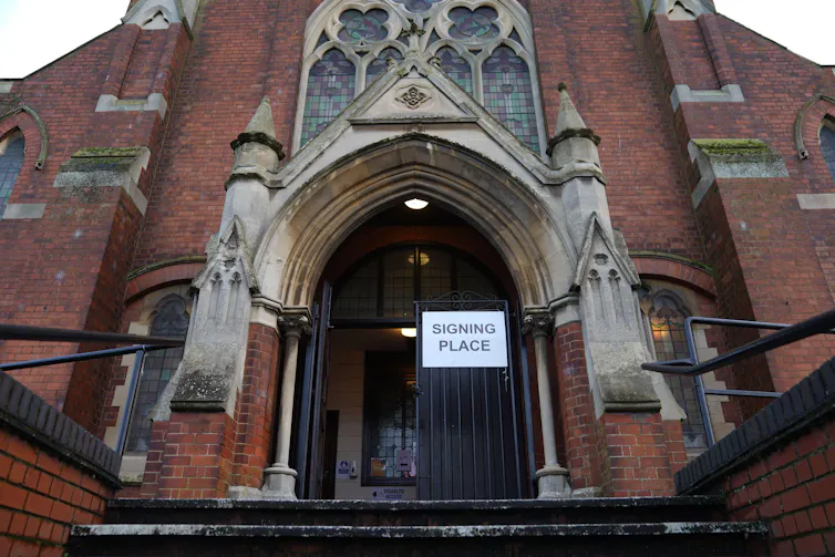The front of a community hall or church with a sign reading 'Signing place'
