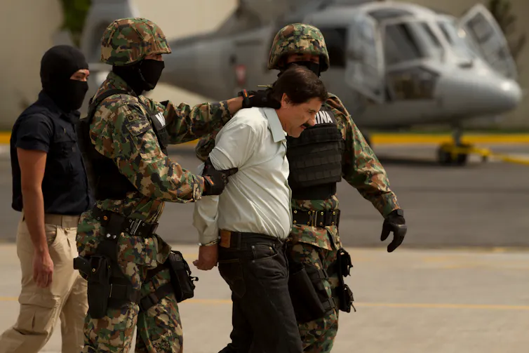 Joaquín 'El Chapo' Guzman being led away by Mexican law enforcement personnel after his arrest.
