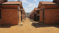 A row of red brick houses very close together on a dusty red road