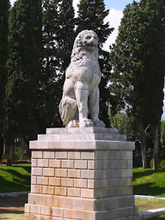 Estatua de un león sobre un pedestal de ladrillo.