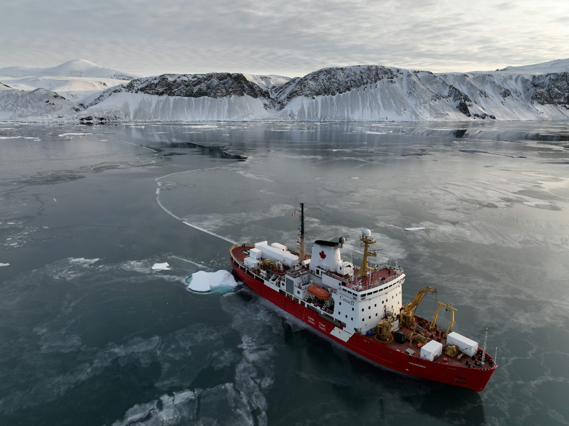 Un brise-glace s'éloigne d'une falaise glacée.