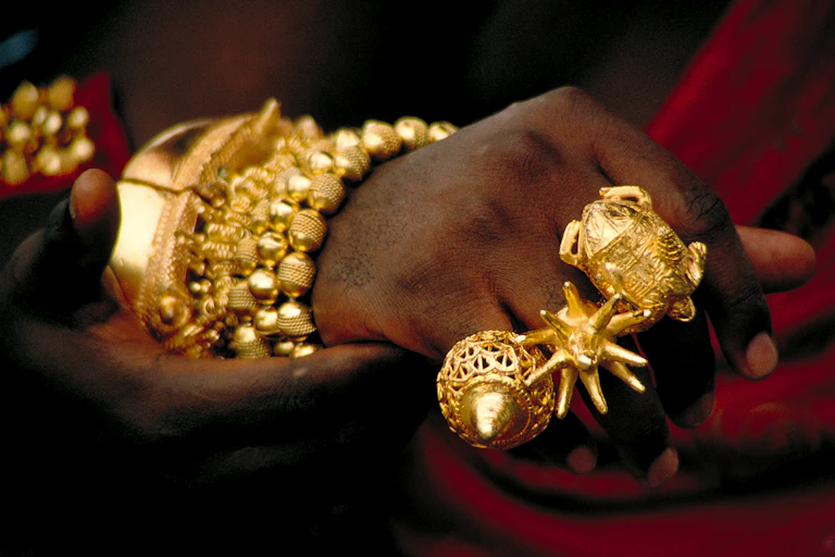 A person's hands and wrist heavily adorned with gold jewellery