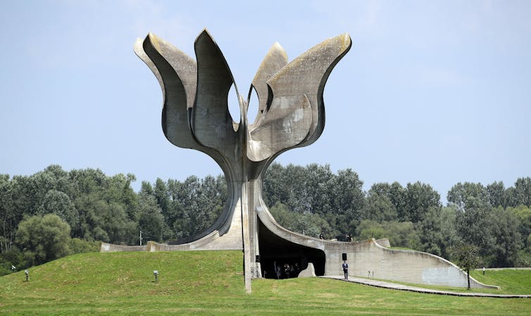 Large concrete sculpture that looks like a flower sprouting from the grass.