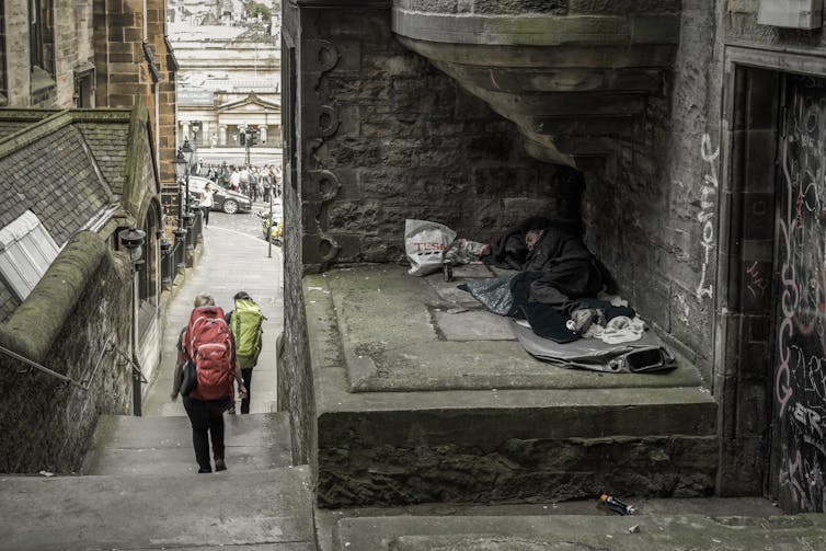 A man sleeping next to passersby in the centre of Edinburgh.