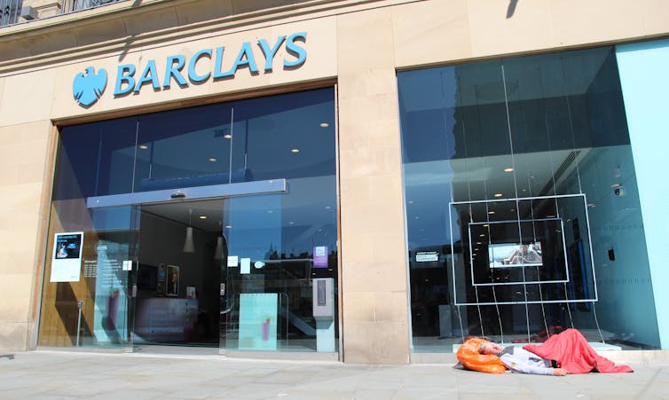 A homeless man sleeping outside a branch of Barclays bank.