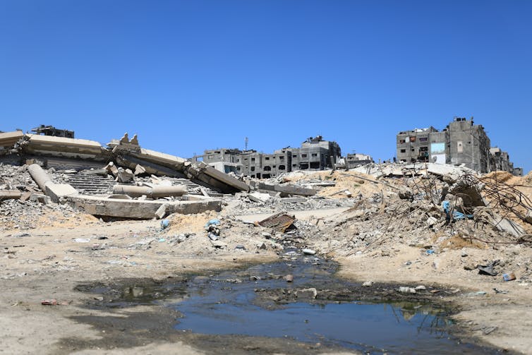 A pool of water is seen in front of rubble.