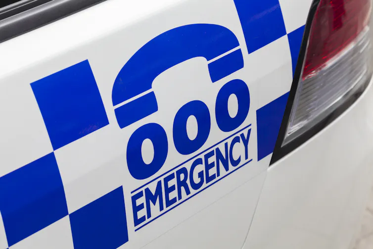 A police sign shows the triple 0 emergency number.