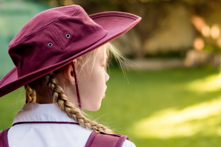 A school student in a broad hat looks into the distance.