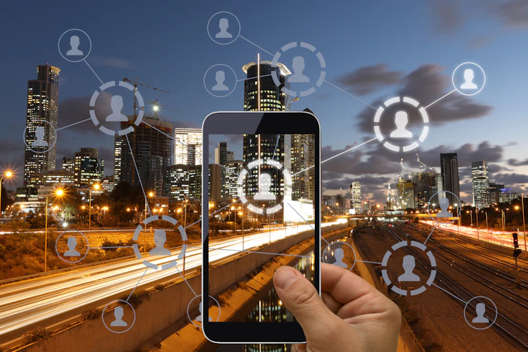A hand holds up a cellphone in front of a cityscape, making avatars pop up in various parts of the image