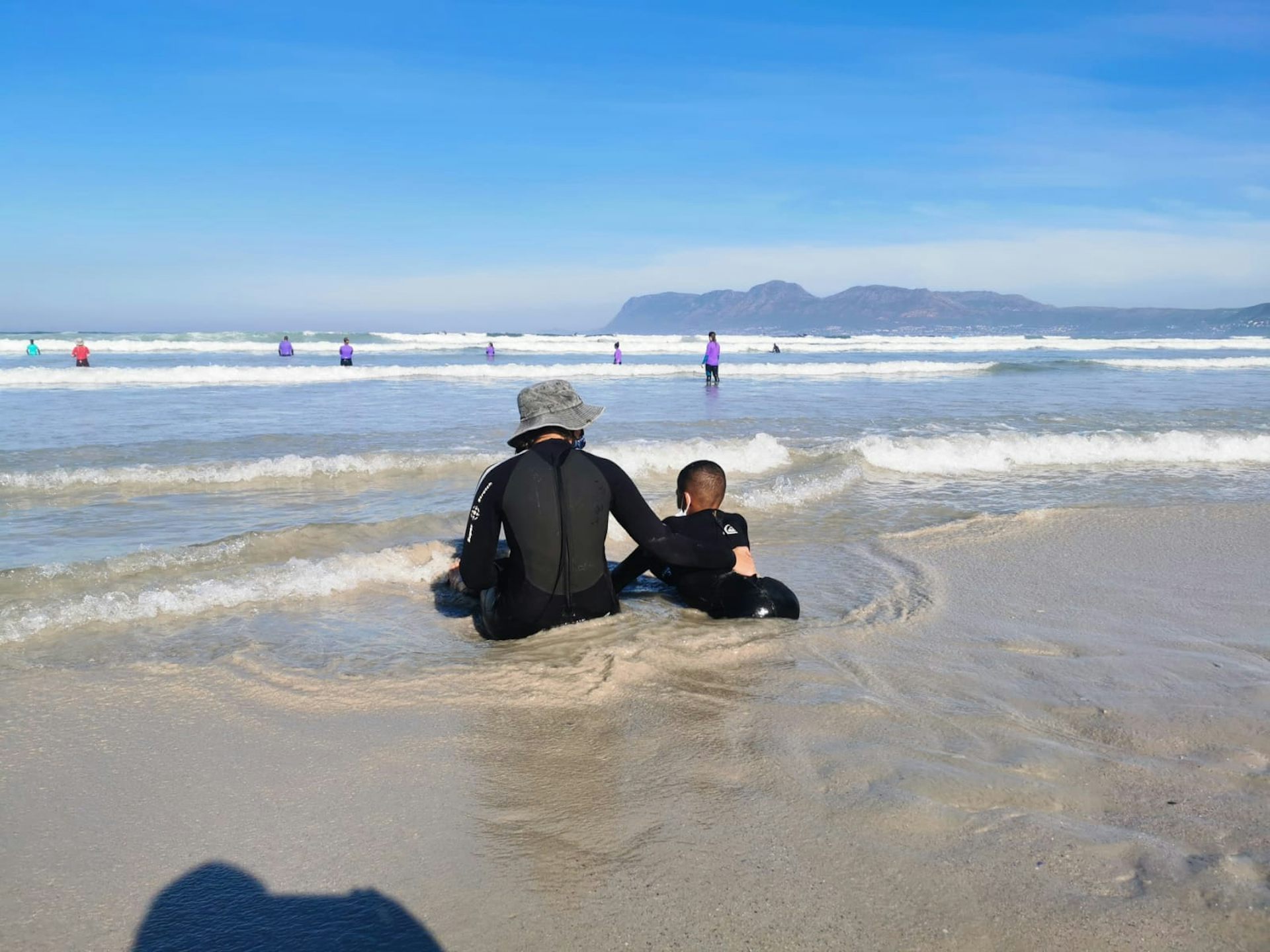 Child and adult sitting in the sea.