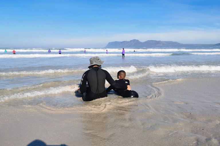 Child and adult sitting in the sea.
