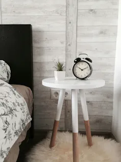 Una mesita con un reloj despertador.