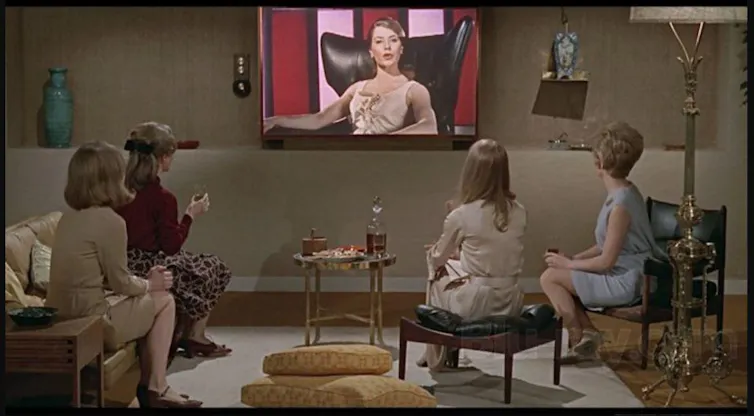 Un grupo de mujeres observa un televisor en un salón.