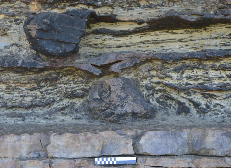 A small scale bar set beneath a dark, rocky protuberance