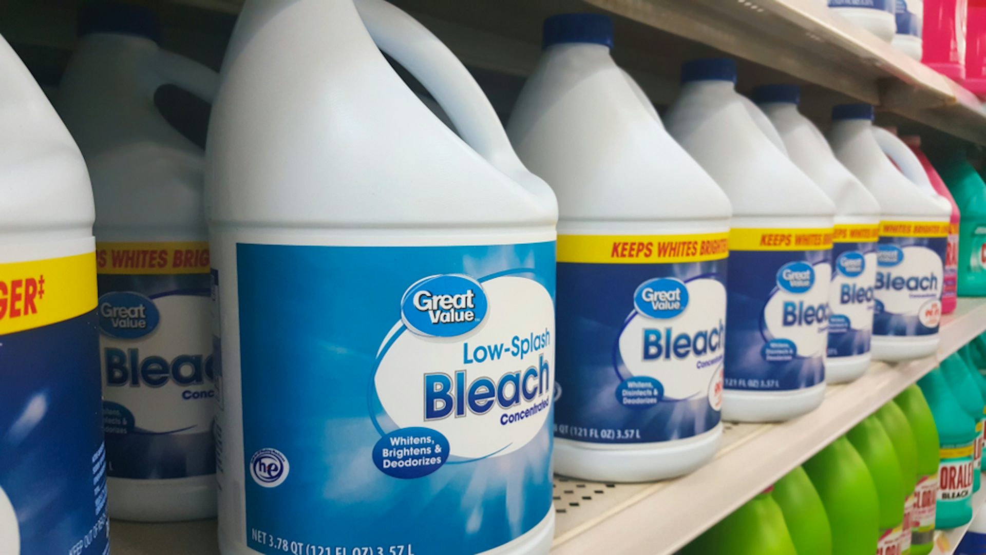 Large bottles of bleach on a shelf.
