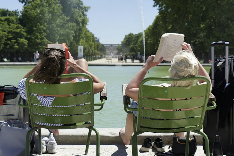 I feel you reinforce dwelling in town: vacationer ethics 2 Two women read in stools placed beside the lake under the sun.