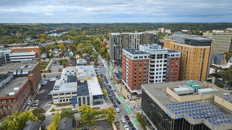 An aerial view of downtown Ann Arbor, Michigan, in autumn with trees changing color and solar panels on rooftops.