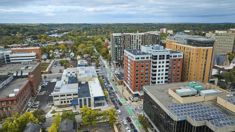 An aerial view of downtown Ann Arbor, Michigan, in autumn with trees changing color and solar panels on rooftops.
