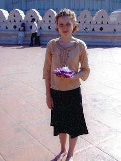 a young woman standing in front of a white wall