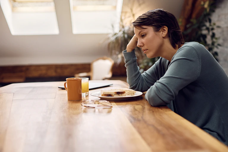 Woman looking sad at breakfast table.