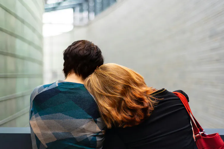 A woman resting her head on the shoulder of another.