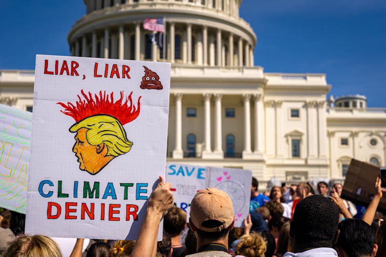 A person holding up a sign mocking President Trump during a climate protest at the White House in Washington D.C.