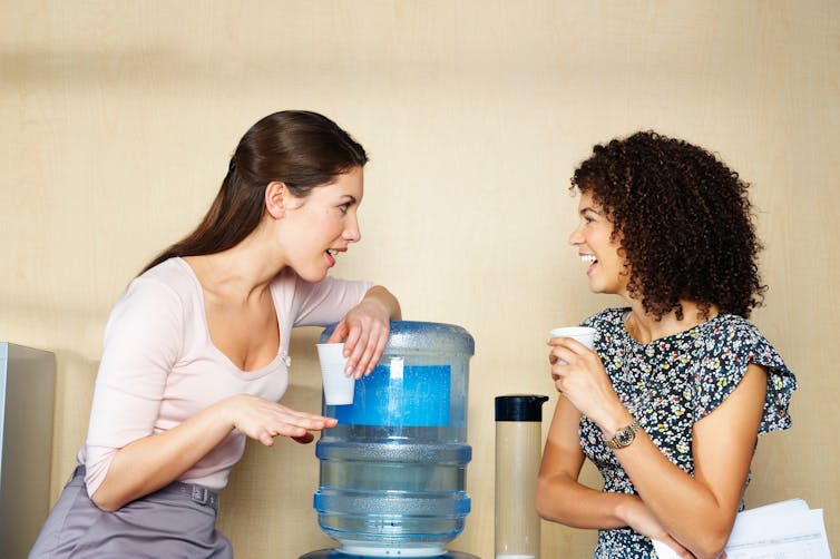 Two women are chatting by water cooler