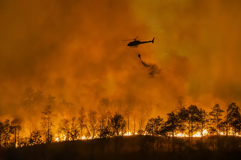Fire fighting helicopter carry water bucket to extinguish the forest fire.