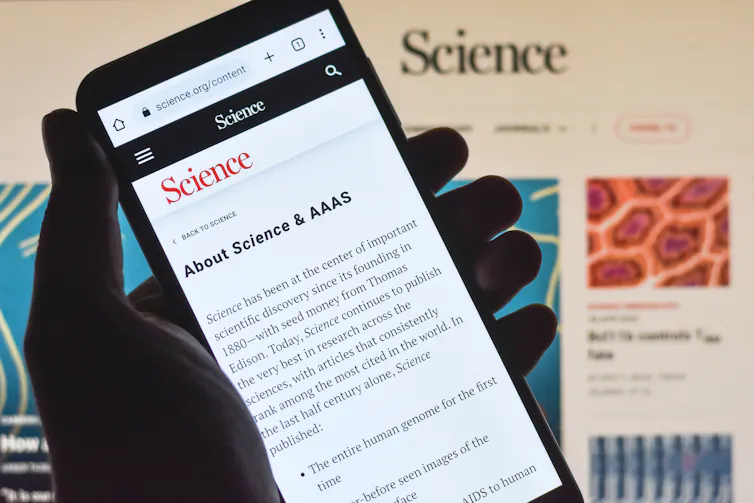 A hand holding a phone displaying the webpage of a scientific journal.