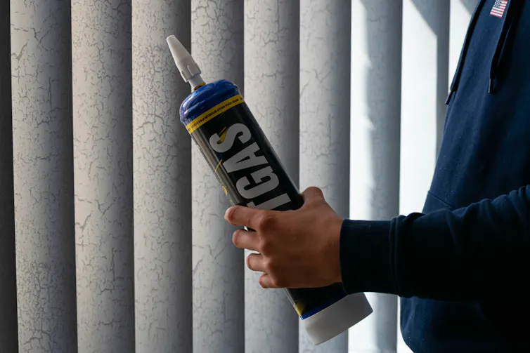 Man's hands holding a large laughing gas canister.