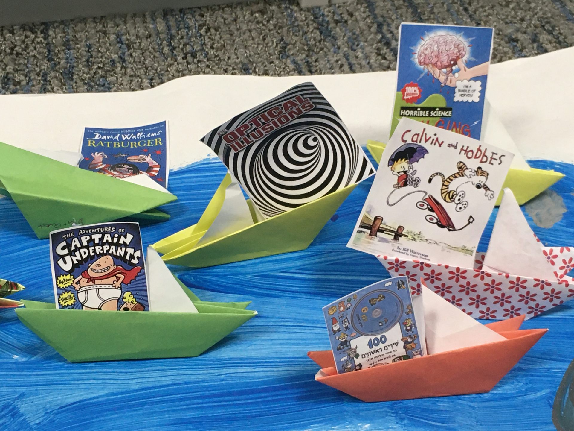 Books in paper boats on blue fabric