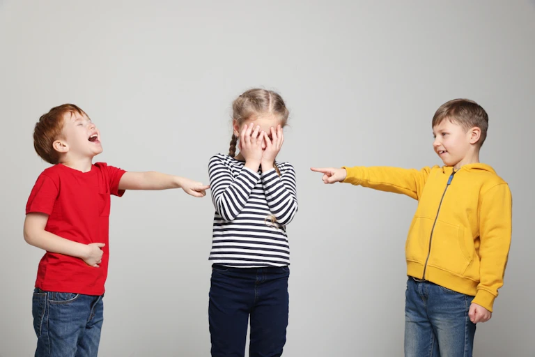 Deux garçons se moquent d'une petite fille