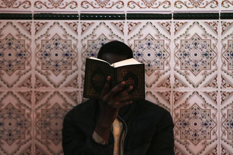 on voit un homme qui lit un livre de prière dans une mosquée