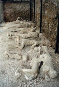 Photo of plaster casts of human bodies lying on the ground.