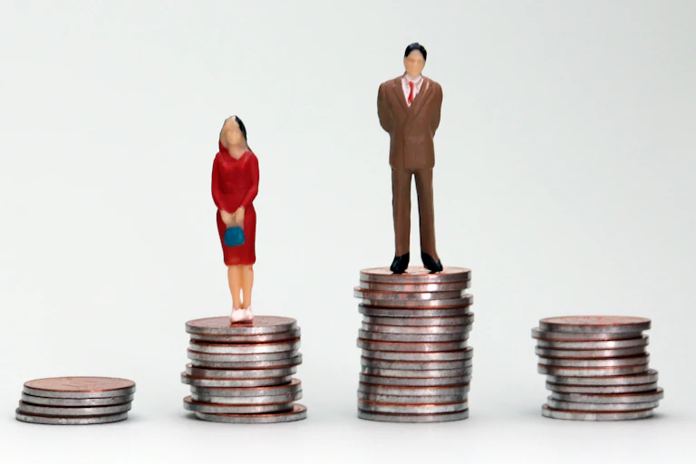 Picture of woman on smaller pile of coins and man on larger pile