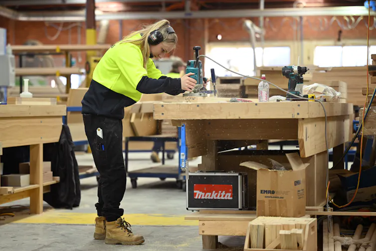 Apprentice using machinery in a warehouse