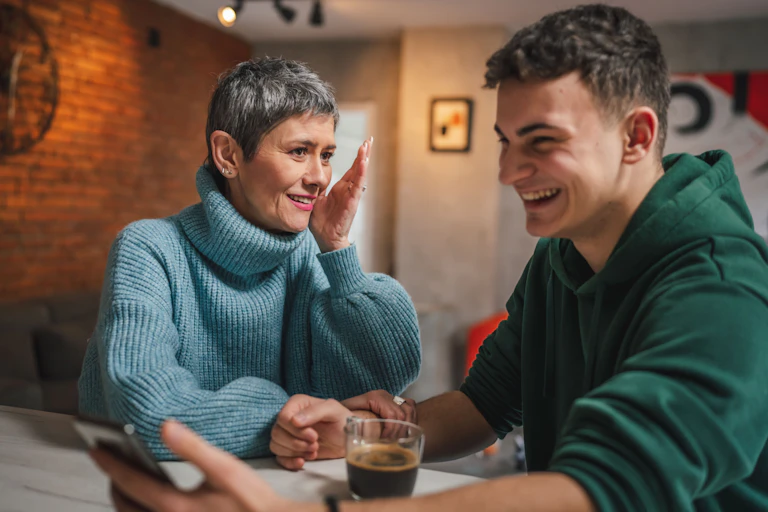A young man and his mother talking over coffee.
