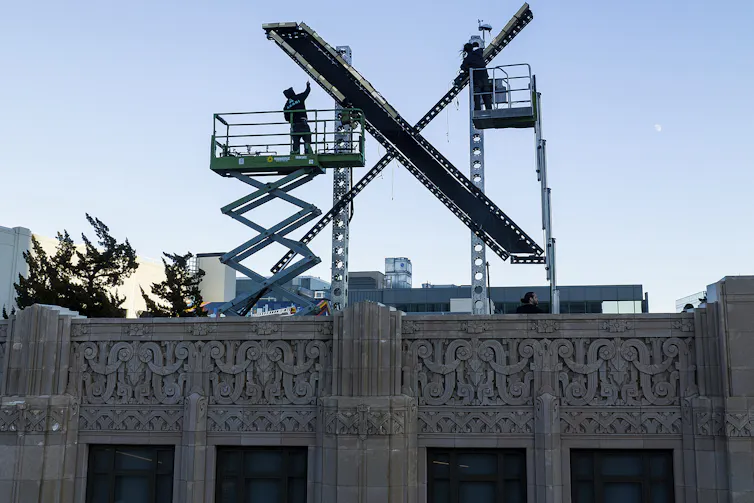 Construction works install a giant X on the top of a building